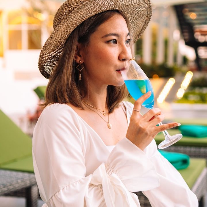 a woman in a hat drinking a glass of wine