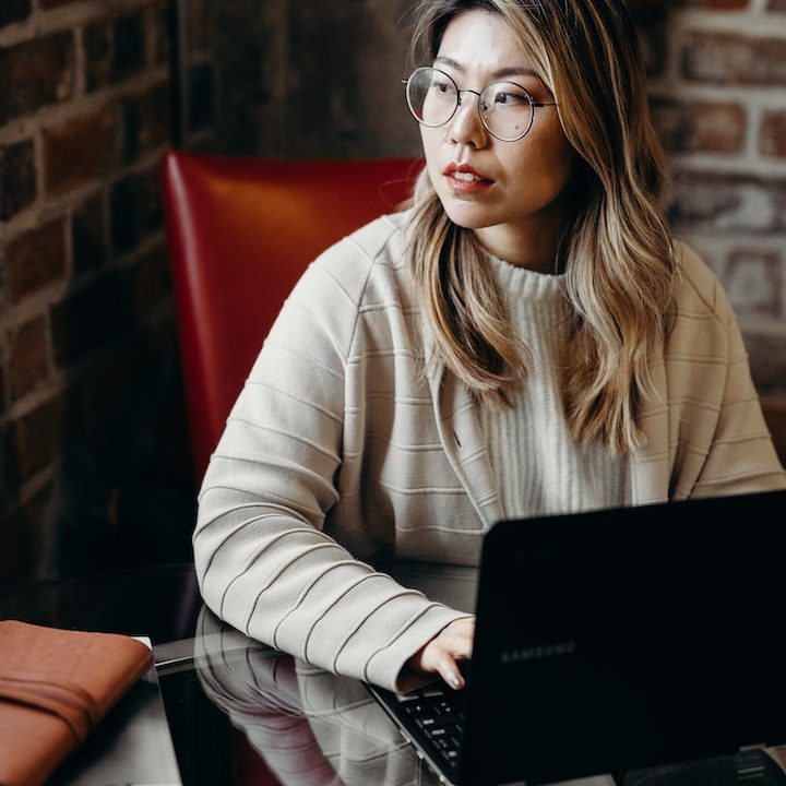 woman looking sideways while holding black laptop computer